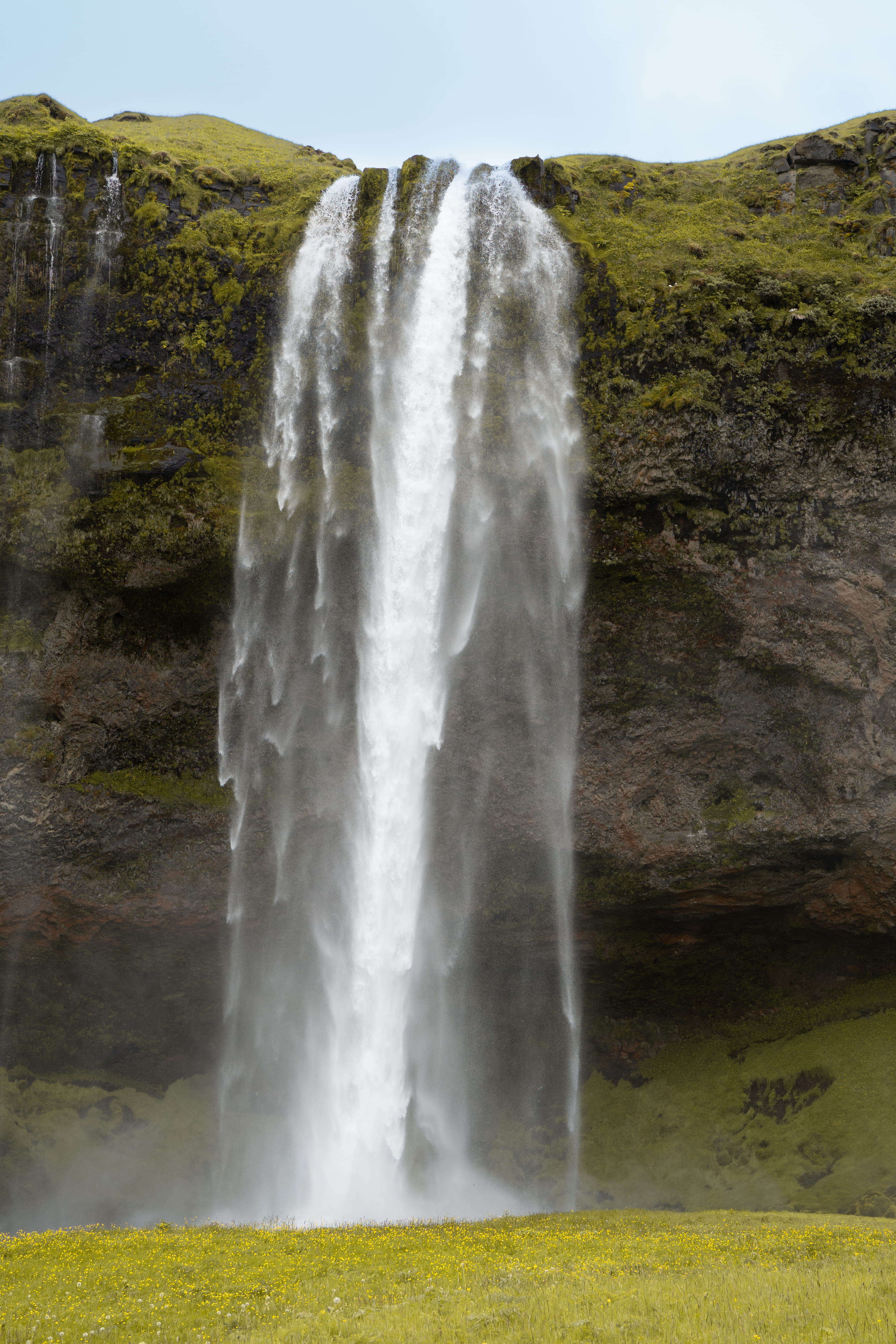 Tall waterfall against mossy rock cliff